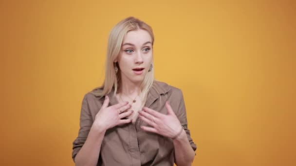 Blondes Mädchen in brauner Bluse über orangefarbenem Hintergrund zeigt Emotionen — Stockvideo