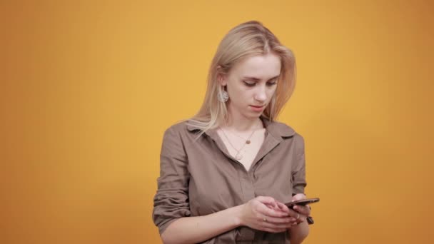 Блондинка в коричневой блузке на изолированном оранжевом фоне показывает эмоции — стоковое видео
