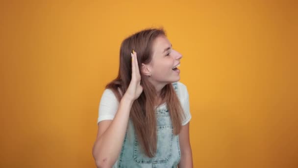 Mujer joven vistiendo camiseta blanca, sobre fondo naranja muestra emociones — Vídeos de Stock