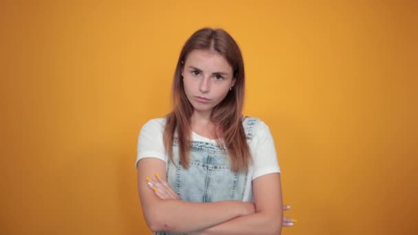 Mujer joven vistiendo camiseta blanca, sobre fondo naranja muestra emociones — Vídeos de Stock