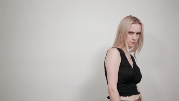 Blonde fille dans une robe noire sur fond blanc isolé montre des émotions — Video