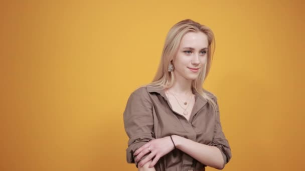 Blonde girl in brown blouse over isolated orange background shows emotions — Stock Video