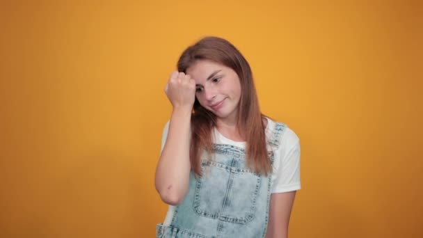 Mujer joven vistiendo camiseta blanca, sobre fondo naranja muestra emociones — Vídeos de Stock