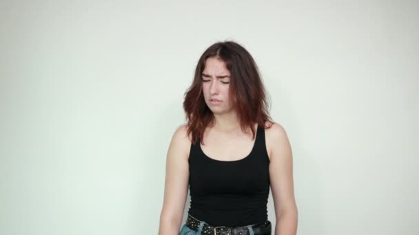 Mooi meisje in zwarte tank top over geïsoleerde witte achtergrond toont emoties — Stockvideo