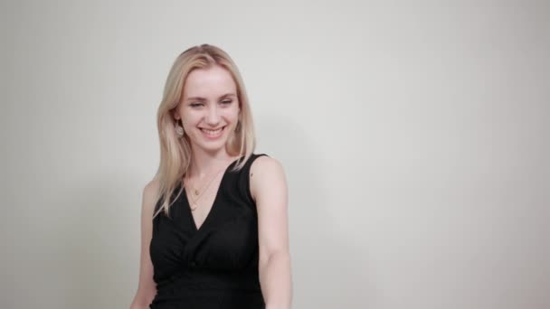 Blonde girl in a black dress over isolated white background shows emotions — Stock Video