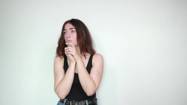 Beautiful girl in black tank top over isolated white background shows emotions — Stock Video