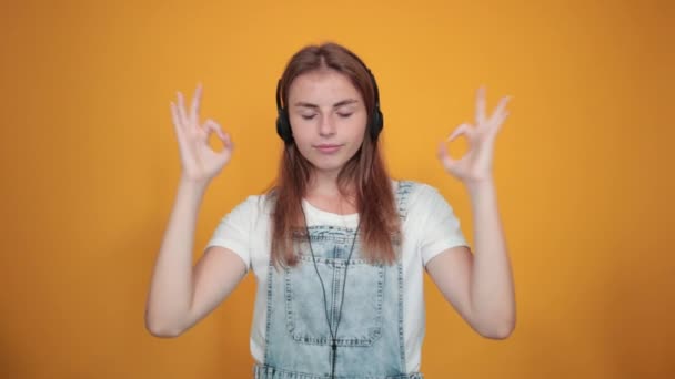 Jonge vrouw draagt wit t-shirt, over oranje achtergrond toont emoties — Stockvideo