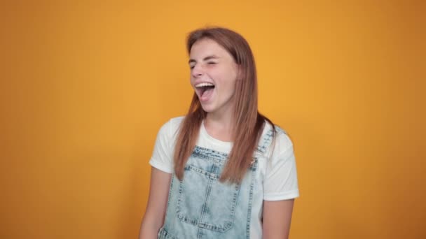 Mujer joven vistiendo camiseta blanca, sobre fondo naranja muestra emociones — Vídeos de Stock