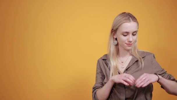 Blonde girl in brown blouse over isolated orange background shows emotions — Stock Video