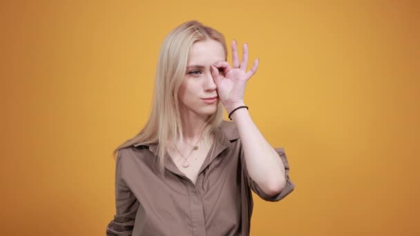 Menina loira em blusa marrom sobre fundo laranja isolado mostra emoções — Vídeo de Stock