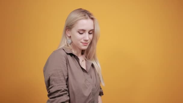 Blonde girl in brown blouse over isolated orange background shows emotions — Stock Video