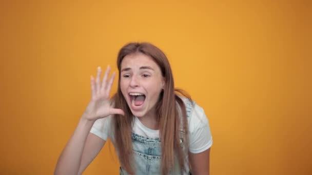 Fiatal nő visel fehér póló, több mint narancssárga háttér mutatja érzelmek — Stock videók