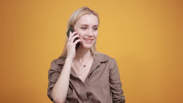 Blonde girl in brown blouse over isolated orange background shows emotions — Stock Video