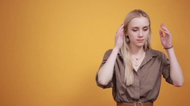 izole turuncu arka plan üzerinde kahverengi bluz sarışın kız duyguları gösterir