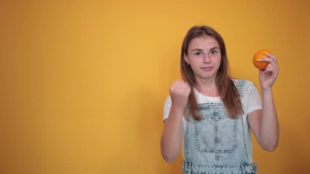 Ung kvinna klädd i vit t-shirt, över orange bakgrund visar känslor — Stockvideo