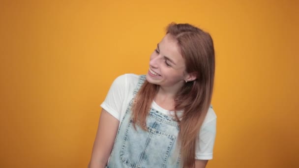 Giovane donna che indossa t-shirt bianca, su sfondo arancione mostra emozioni — Video Stock