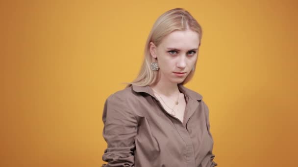 Blondes Mädchen in brauner Bluse über orangefarbenem Hintergrund zeigt Emotionen — Stockvideo
