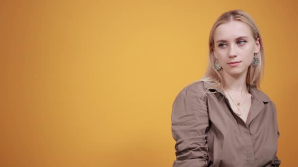 Szőke lány barna blúz át elszigetelt narancssárga háttér mutatja érzelmek — Stock videók