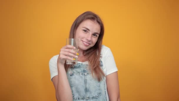 Молода жінка в білій футболці на помаранчевому фоні показує емоції — стокове відео