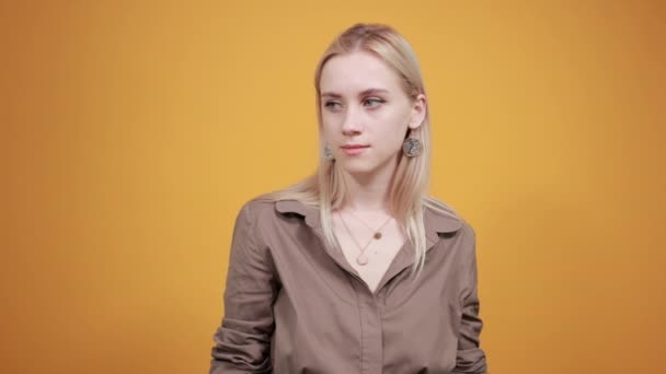 Ξανθιά κορίτσι σε καφέ μπλούζα πάνω από απομονωμένο πορτοκαλί φόντο δείχνει τα συναισθήματα — Αρχείο Βίντεο