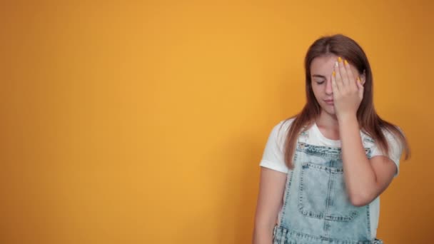 Jovem mulher vestindo camiseta branca, sobre fundo laranja mostra emoções — Vídeo de Stock