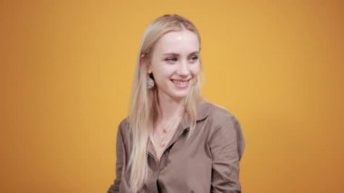 izole turuncu arka plan üzerinde kahverengi bluz sarışın kız duyguları gösterir