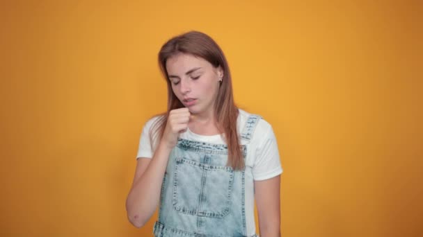 Mujer joven vistiendo camiseta blanca, sobre fondo naranja muestra emociones — Vídeos de Stock