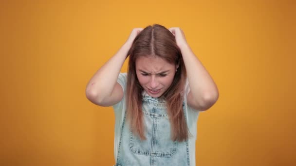 Mujer joven vistiendo camiseta blanca, sobre fondo naranja muestra emociones — Vídeos de Stock