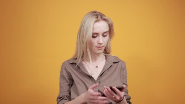 Ξανθιά κορίτσι σε καφέ μπλούζα πάνω από απομονωμένο πορτοκαλί φόντο δείχνει τα συναισθήματα — Αρχείο Βίντεο