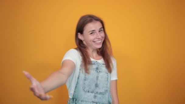 Mujer joven vistiendo camiseta blanca, sobre fondo naranja muestra emociones — Vídeos de Stock