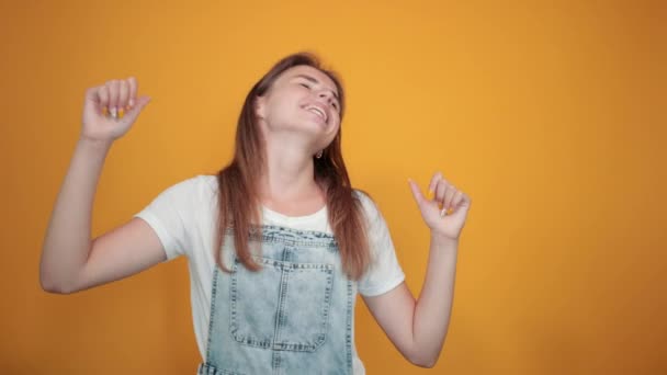 Mujer joven vistiendo camiseta blanca, sobre fondo naranja muestra emociones — Vídeos de Stock