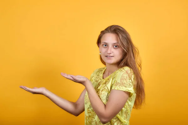 Brunette meisje in geel t-shirt over geïsoleerde oranje achtergrond toont emoties — Stockfoto