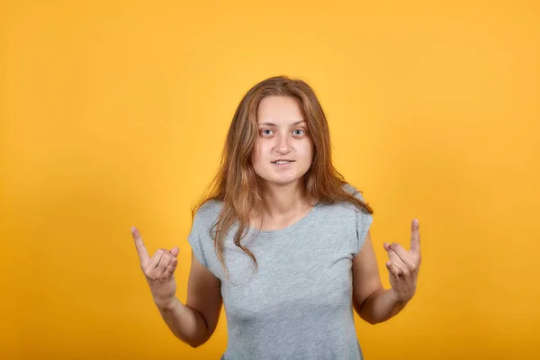 Brunette meisje in grijs t-shirt over geïsoleerde oranje achtergrond toont emoties — Stockfoto