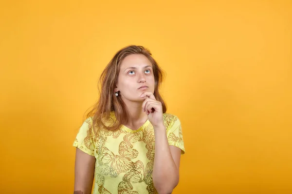 Chica morena en camiseta amarilla sobre fondo naranja aislado muestra emociones —  Fotos de Stock