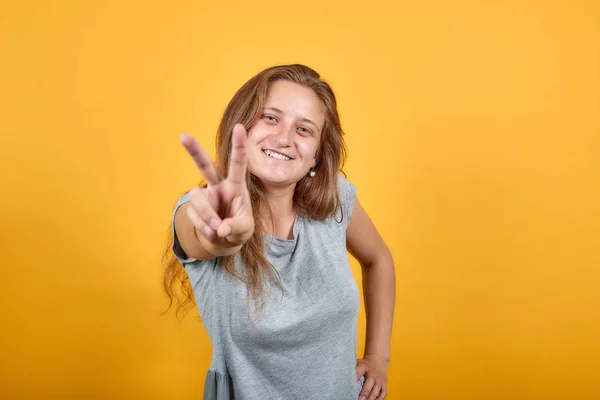 Morena chica en gris camiseta sobre aislado naranja fondo muestra emociones —  Fotos de Stock