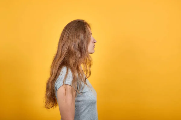 Brunette meisje in grijs t-shirt over geïsoleerde oranje achtergrond toont emoties — Stockfoto