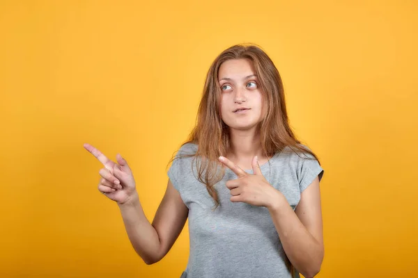 Brunette meisje in grijs t-shirt over geïsoleerde oranje achtergrond toont emoties — Stockfoto