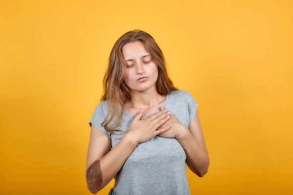 Брюнетка в серой футболке на изолированном оранжевом фоне показывает эмоции — стоковое фото