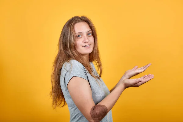 Brunette meisje in grijs t-shirt over geïsoleerde oranje achtergrond toont emoties — Stockfoto