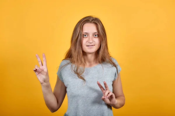 Brunette meisje in grijs t-shirt over geïsoleerde oranje achtergrond toont emoties — Stockfoto
