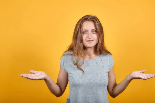 Brunette meisje in grijs t-shirt over geïsoleerde oranje achtergrond toont emoties — Stockfoto