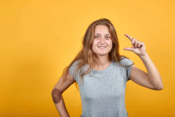 Brunette meisje in grijs t-shirt over geïsoleerde oranje achtergrond toont emoties — Stockfoto