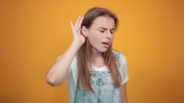 Jovem mulher vestindo camiseta branca, sobre fundo laranja mostra emoções — Vídeo de Stock