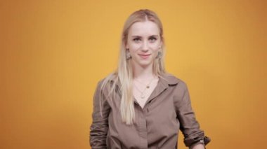 izole turuncu arka plan üzerinde kahverengi bluz sarışın kız duyguları gösterir