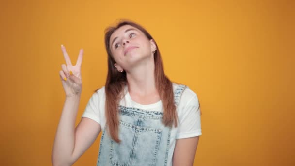 Jovem mulher vestindo camiseta branca, sobre fundo laranja mostra emoções — Vídeo de Stock