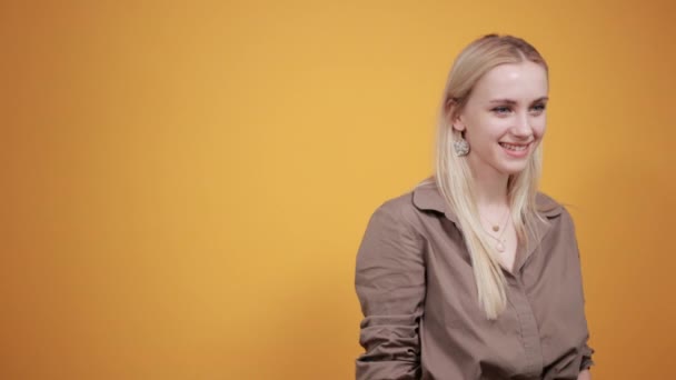 Izole turuncu arka plan üzerinde kahverengi bluz sarışın kız duyguları gösterir — Stok video