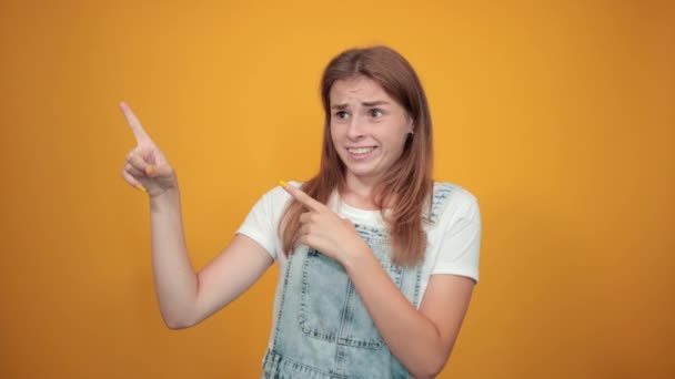 Mujer joven vistiendo camiseta blanca, sobre fondo naranja muestra emociones — Vídeos de Stock