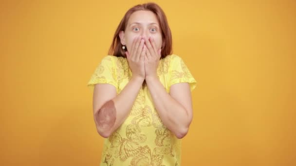 Chica morena en camiseta amarilla sobre fondo naranja aislado muestra emociones — Vídeo de stock