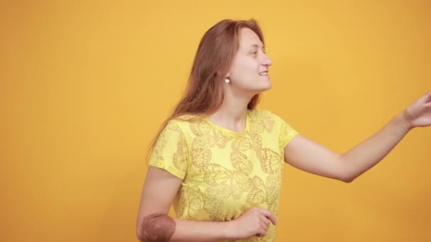黑发女孩在黄色T恤在孤立的橙色背景显示情绪 — 图库视频影像