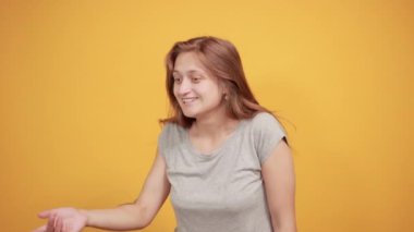 izole turuncu arka plan üzerinde gri t-shirt esmer kız duyguları gösterir